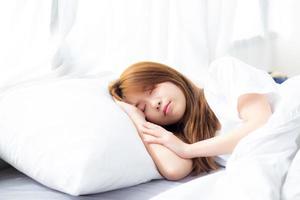 Young asian woman sleep lying in bed with head on pillow. photo