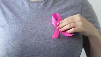 Mês de conscientização do câncer de mama. mulher atribui uma fita rosa à sua t-shirt. conceito de suporte. promoção de campanha contra o câncer.