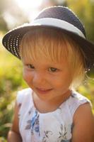 linda niña rubia sonriente con un sombrero azul foto