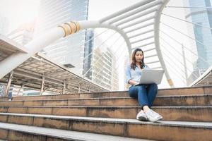 mujer feliz trabajando con ordenador portátil. concepto de éxito y felicidad. concepto de tecnología y estilo de vida ciudad y tema urbano. vida feliz en el tema al aire libre foto