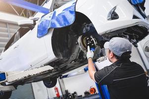 técnico de automóviles asiático masculino mantenimiento de automóviles para clientes de acuerdo con la lista de verificación de mantenimiento de vehículos especificada. desgaste de las pastillas de freno de disco reparación automotriz en el vehículo. servicio de control de inspección de seguridad foto