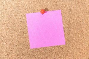 Blank pink note and push pin on cork board. Template to ad text or drawings photo