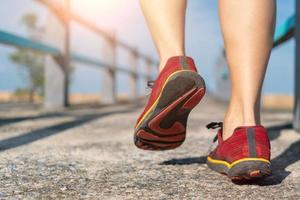 Woman wear running shoe on to walking and running on nature green background.Health exercise. photo