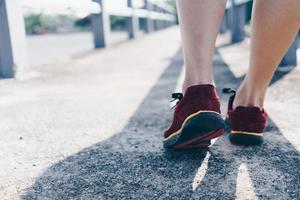 Woman wear running shoe on to walking and running on nature green background.Health exercise. photo