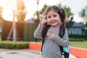 niña feliz disfruta de ir a la escuela. volver al concepto de escuela y educación. tema de estilo de vida familiar de vida feliz. gesto de alegría foto