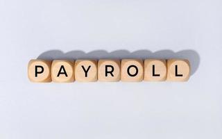 Payroll word on wooden block isolated on gray background photo