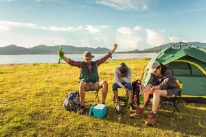 turistas borrachos haciendo fiesta mientras acampa y hace un picnic en el campo de la pradera. fondo de montaña y lago. concepto de personas y estilos de vida. actividad al aire libre y tema de ocio. tema de mochileros y excursionistas foto