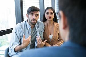 Psychotherapist inquiring about symptoms occurring within mind from patients with mental health problems in hospital. Group psychotherapy for support and helping worried man to change negative mindset photo