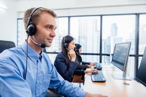 Group of young profession call center operator agent with headsets working in office. Business telemarketing service people concentrating on having conversation work and talking to customer friendly photo