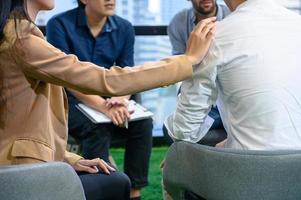 Psychotherapist inquiring about symptoms occurring within mind from patients with mental health problems in hospital. Group psychotherapy for support and helping worried man to change negative mindset photo