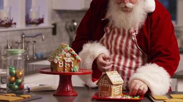 Papá Noel en la cocina decorando la casa de pan de jengibre video