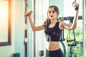Asian young woman doing elastic rope exercises at cross fitness gym. Strength training and muscular Beauty and Healthy concept. Sport equipment and Sport club center theme