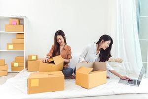 Young Asian woman startup small business entrepreneur SME distribution warehouse with parcel mail box. Owner home office concept. Online marketing and product packaging and delivery service photo