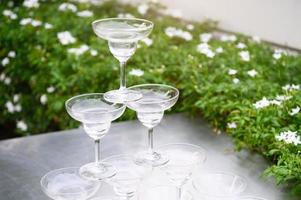 Primer grupo de apilamiento de copas de vino de martini en la barra de mostrador al aire libre en el jardín para preparar la fiesta de celebración