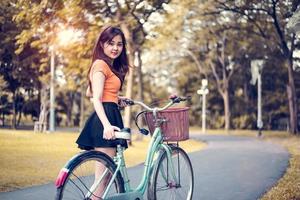 Retrato de mujer asiática en parque público con bicicleta. concepto de personas y estilos de vida. tema de relajación y actividad foto