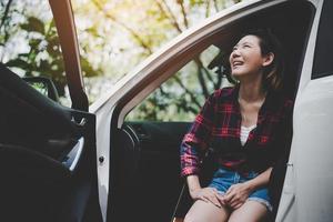 Beauty Asian woman looking to nature and having fun at outdoors summer with Ukulele in white car. Traveling of photographer concept. Hipster style and Solo woman theme. Lifestyle and Happiness theme photo