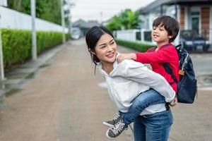 Single mom carrying and playing with her children near home with villa street background. People and Lifestyles concept. Happy family and Home sweet home theme. Outdoors and nature theme photo