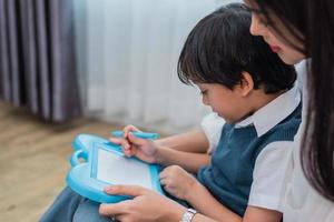 Asian mom teaching cute boy to drawing in chalkboard together. Back to school and Education concept. Family and Home sweet home theme. Preschool kids theme photo