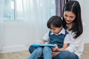 Asian mom teaching cute boy to drawing in chalkboard together. Back to school and Education concept. Family and Home sweet home theme. Preschool kids theme photo