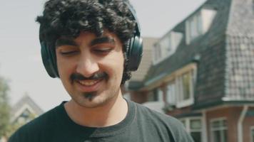 Man with headphone smiles walks and dances on the street