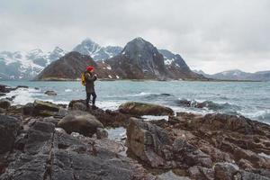 Traveller photographer taking nature photo standing on rocks against background of sea and mountains