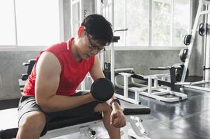 Entrenamiento de hombre asiático musculoso fuerte en el gimnasio haciendo ejercicios de bíceps. concepto de entrenamiento con pesas.