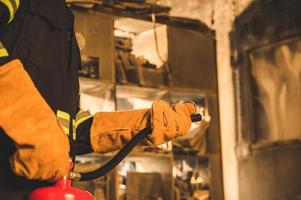 Cerrar mano bombero usando extintor de incendios foto