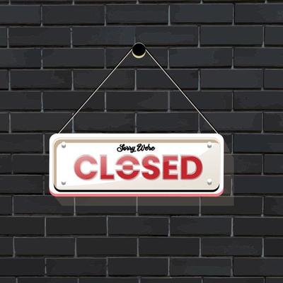 hanging closed signage with a black brick background
