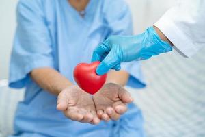 El médico le da un corazón rojo al paciente asiático mayor o anciano, concepto médico fuerte y saludable