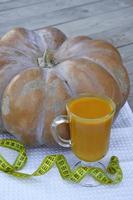 Pumpkin on a wooden background and a glass of pumpkin juice. photo