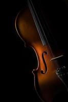 Violin on a black background in oblique light on one side photo