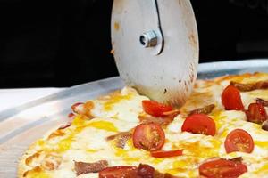 Slicing fresh made Italian pizza, in kitchen photo