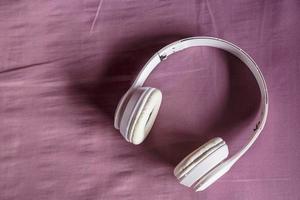 White headphones on purple background. Music concept. photo