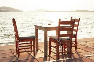 Mesa y sillas en el restaurante de la playa al atardecer foto