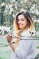 pretty girl enjoys blooming magnolia trees, her long hair in motionn photo