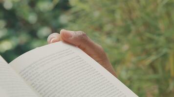 Close up of hand holding opened book in green environment video