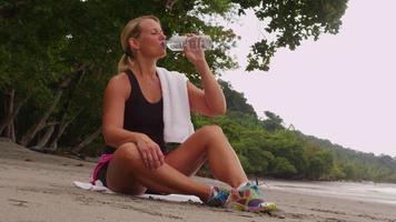 mujer descansando y bebiendo agua después de correr. filmado en rojo épico para una resolución de alta calidad de 4k, uhd, ultra hd. video