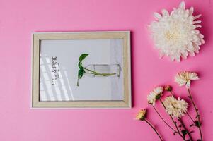 white photo frame with flower on pink background