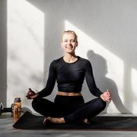 young blond woman doing yoga or meditating at home photo