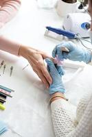 Manicure master in gloves using nail file to buff the nail of a client photo