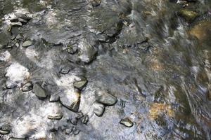 Rushing water flowing over rocks in a stream photo