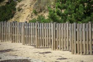 Rows of a wooden fence on a sandy beach