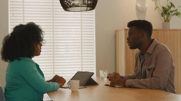 mulher e homem sentados à mesa conversando video