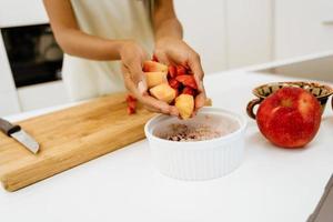 Black young woman making cereal with fruits at kitchen photo