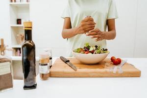 Black young woman making salad while cooking lunch at kitchen