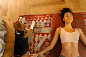 Black young woman laying on floor at home and resting after yoga practice photo