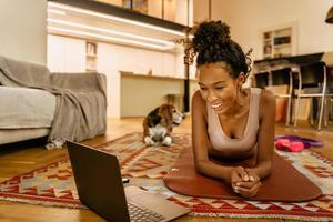Black young woman smiling using laptop and doing exercises photo
