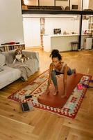 Black young woman using laptop during yoga at home photo