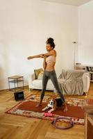 Black young woman doing exercise during yoga with her dog photo