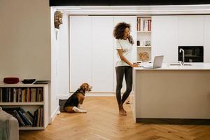 Black young woman using laptop while standing at home photo